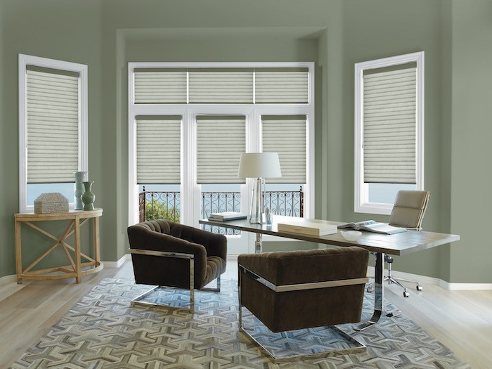 A home office with muted green walls and espresso brown chairs.